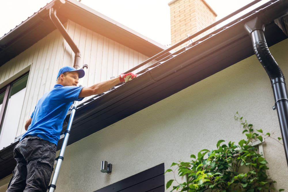 man cleaning house gutters