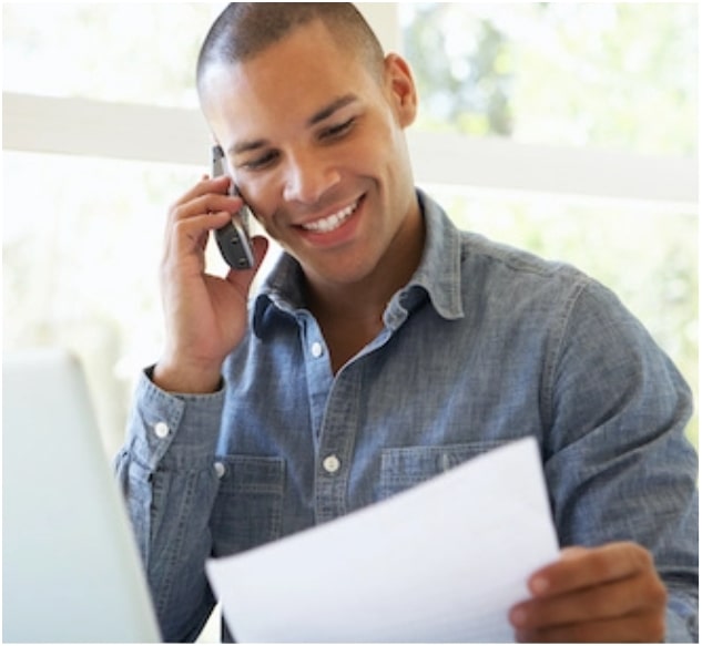 A man on a phone looking at a piece of paper