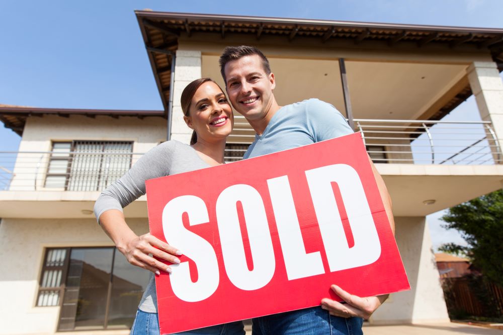 couple with sold sign in hands